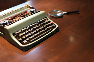 Retro typewriter and a magnifying glass on a wooden table