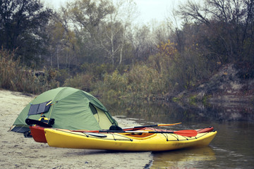 Camping with kayaks on the river bank.