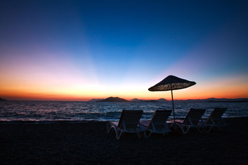 Sun loungers on beach on background of beautiful dawn sky