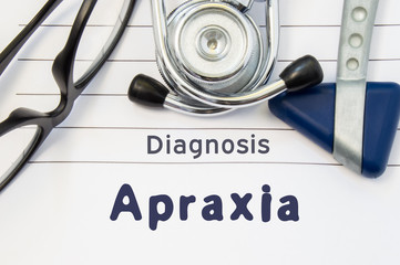 Neurological diagnosis of Apraxia. Neurological hammer, stethoscope and doctor's glasses lie on doctor workplace on sheet of notebook, labeled with the title of medical diagnosis of Apraxia