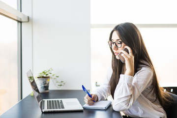 young woman worker sitting in office with phone.