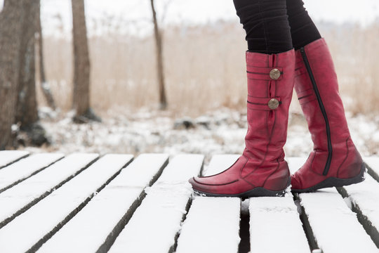 Woman walking in winter day. Winter boots on legs. Active lifestyle at nature.