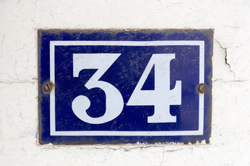 Number 34 (thirty four) in white on a blue metal plate