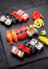 Obraz na płótnie Canvas Japanese cuisine. Sushi set on a stone plate and black concrete background.
