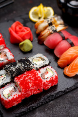 Japanese cuisine. Sushi set on a stone plate and black concrete background.