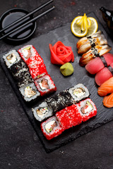 Japanese cuisine. Sushi set on a stone plate and black concrete background.