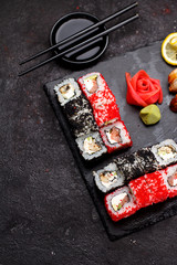 Japanese cuisine. Sushi set on a stone plate and black concrete background.