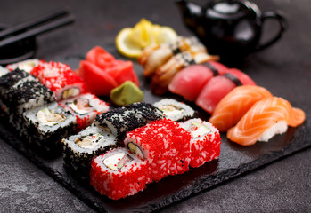 Japanese cuisine. Sushi set on a stone plate and black concrete background.
