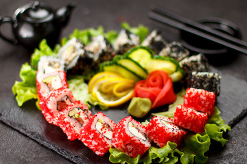Japanese cuisine. Sushi set on a stone plate and black concrete background.