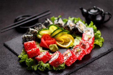 Japanese cuisine. Sushi set on a stone plate and black concrete background.