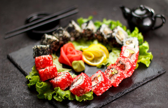 Japanese cuisine. Sushi set on a stone plate and black concrete background.
