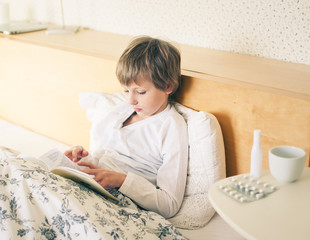 Ill kid boy reading book at home    © Tatiana Murr