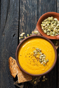 Delicious pumpkin soup on wooden table, top view vertical