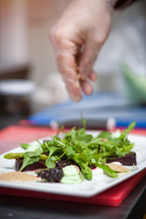 Male chef cooking salad with arugula and beet