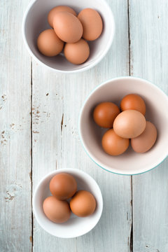 Bowls with chicken eggs on the white wooden table vertical