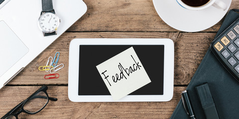 Note saying "Feedback" note on device at office desktop
