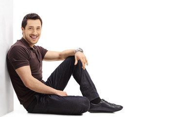 Young guy sitting on the floor and leaning against a wall