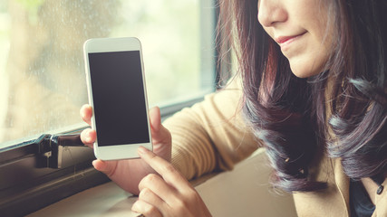 Mockup image of a beautiful asian woman using on the smart phone with blank black screen in the room , feeling happy and smiley face and  reflections in glass 