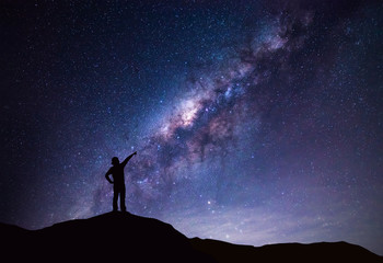 Milky Way landscape. Silhouette of Happy woman pointing to the bright star.