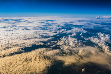 White clouds and blue sky seen from the window of an airplane.