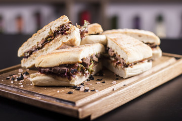 Meat sandwiches placed on a wooden plate. Delicious sandwiches served at the restaurant. Delicious food service.