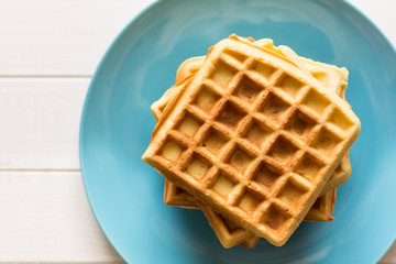 Belgian waffles with honey and cranberries on blue plate. Selective focus