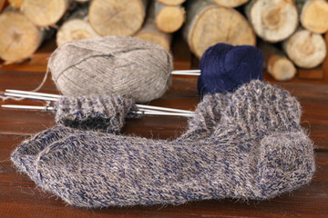 Fototapeta na wymiar Вязаные шерстяные носки и пряжа лежат на столе на деревянном фоне.