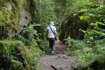 Fototapeta premium eine frau mit sonnenhut geht zwischen bemoosten felsen im oberen püttlachtal