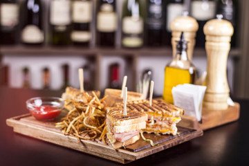 Meat sandwiches placed on a wooden plate. Delicious sandwiches served with french fries at the restaurant. Delicious food service.
