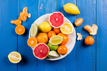 various types of citrus fruit on a blue painted wooden background