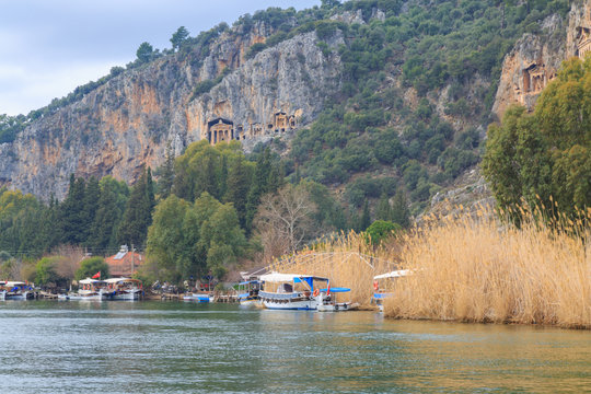Dalyan river with boats and king's tombs.