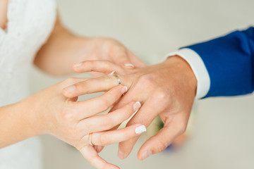 Obraz na płótnie Canvas Closeup of groom placing ring on brides finger on their