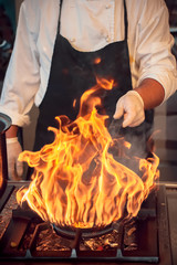 chef in hotel kitchen prepare vegetable food with fire