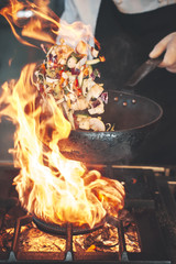 chef in hotel kitchen prepare vegetable food with fire