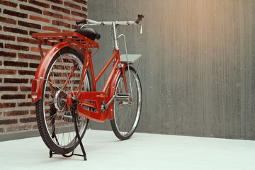 vintage red bicycle parked along the rough concrete with brick w