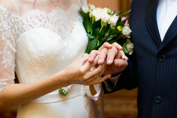 Closeup of groom placing ring on brides finger on their