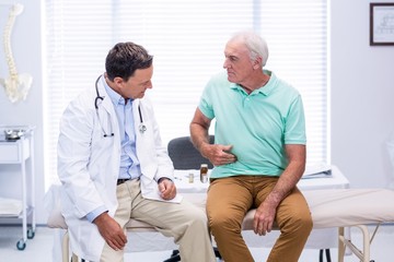 Senior man showing stomach ache pain to doctor - Powered by Adobe