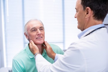 Obraz premium Doctor examining senior patients neck