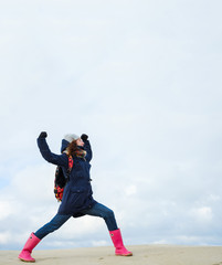 Obraz premium energetic funny young woman enjoying life and posing on on winter beach. energy, strength, power, success concept