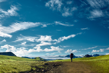 Fototapeta na wymiar man hiker on the trail in the Islandic mountains. Trek in National Park Landmannalaugar, Iceland. valley is covered with bright green moss