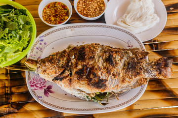Grilled tilapia on dish and on bamboo table