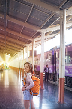 Young woman with retro suitcase and camera on railway platform