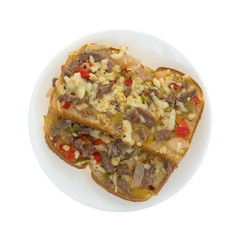 Top view of a steak cheese and vegetable sandwich on a plate isolated on a white background.