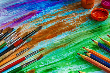 Artistic brushes and colored pencils on a colorful background.Flat-view