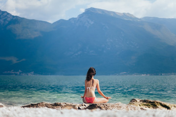 Fototapeta na wymiar Woman meditating in Lotus Pose on beautiful beach of mountain la