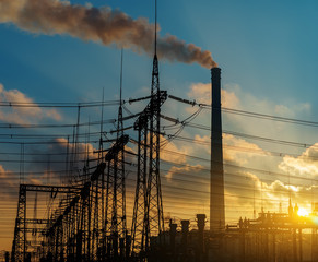 distribution electric substation with power lines and transformers, at sunset.