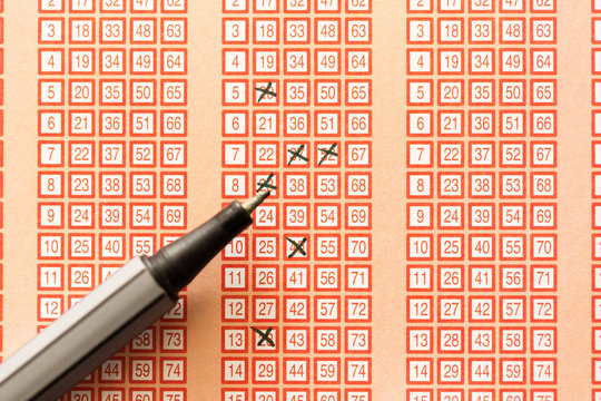 pen and bingo lotto lottery ticket with crossed numbers