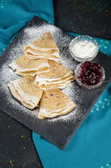 Russian pancake blini with fresh cream and berry jam on dark bac
