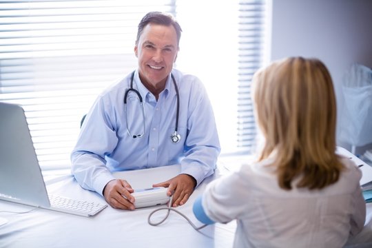 Portrait of doctor checking blood pressure of a patient