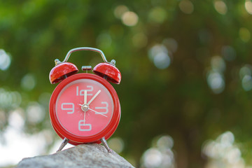 Alarm clock on stone with blurred background.